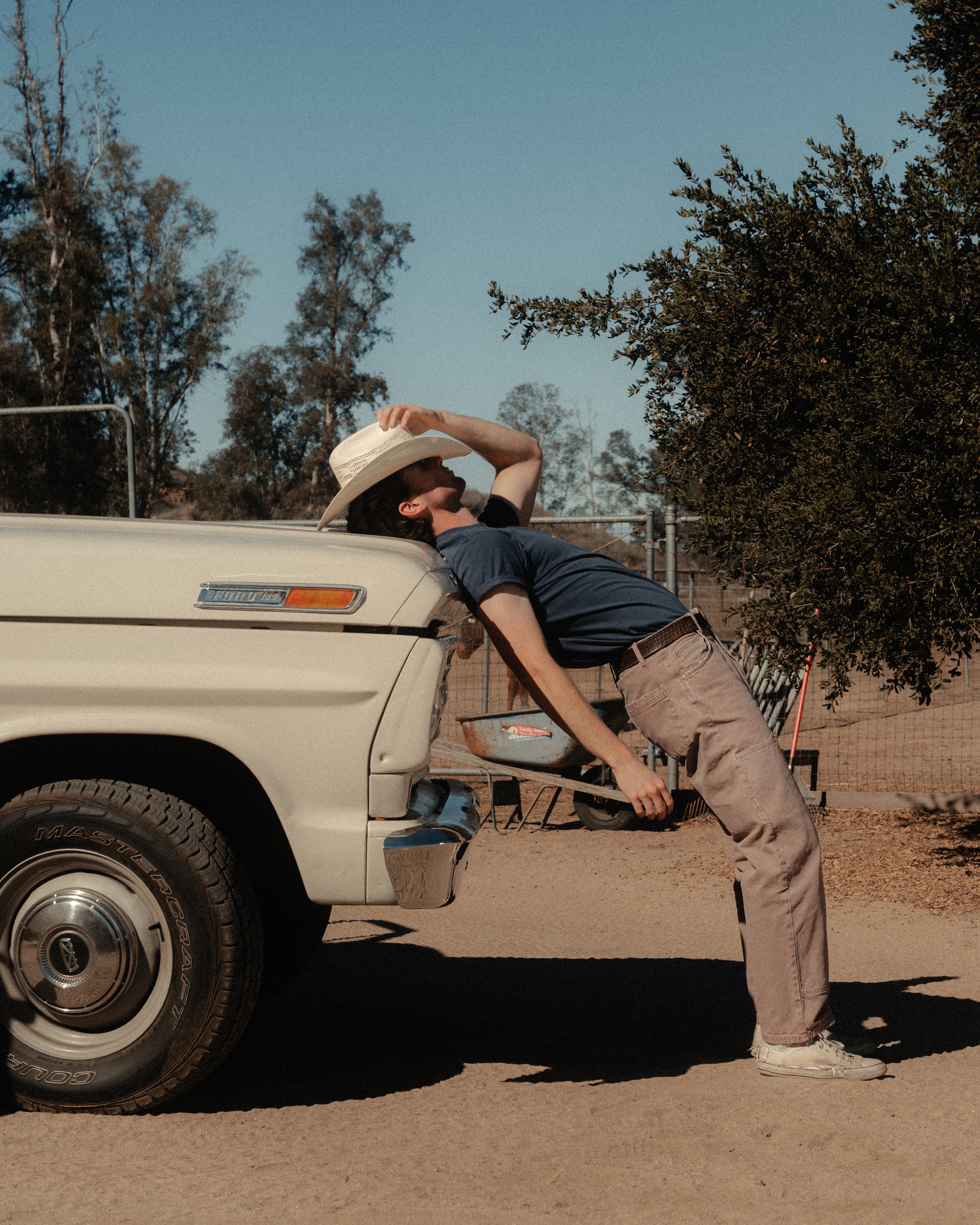 Person leaning on an old truck in a desert setting
