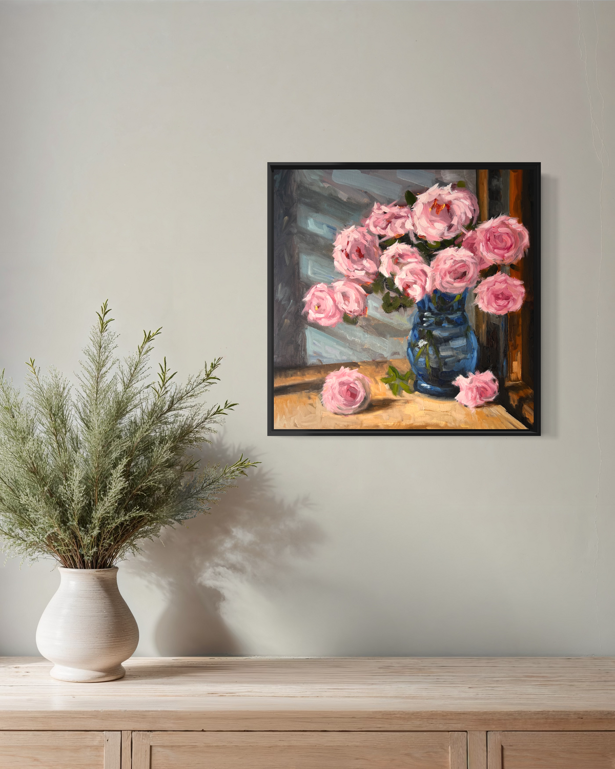 "Pink Roses" original oil painting by John Wellington — black floater frame on a neutral wall above a wooden console