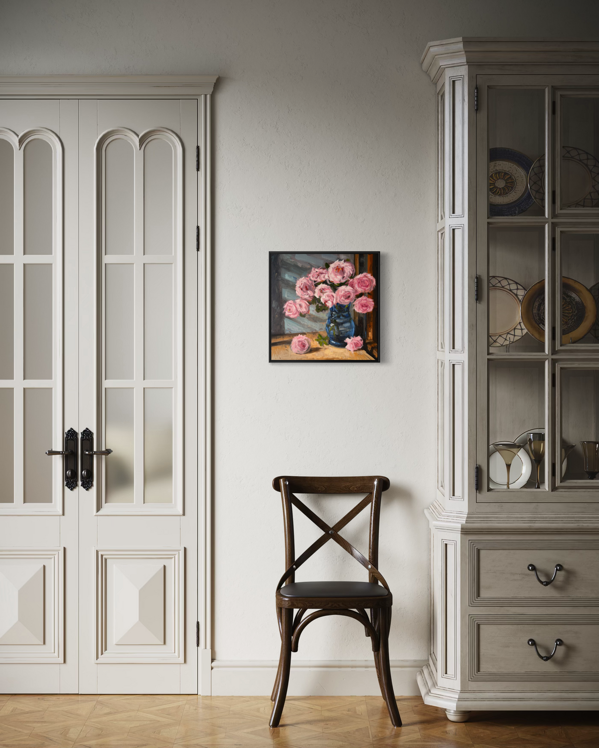 "Pink Roses" original oil painting by John Wellington — framed beside French doors and a vintage bistro chair
